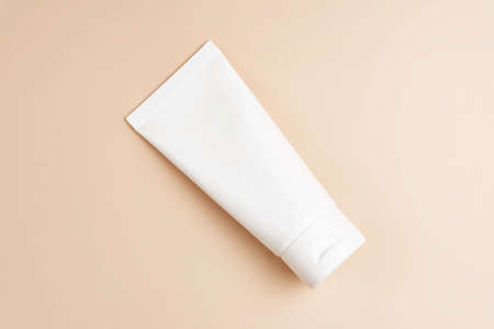Beauty product concept. White tube of cream on beige background. Top view. Trendy showcase. Unbranded package.の写真素材