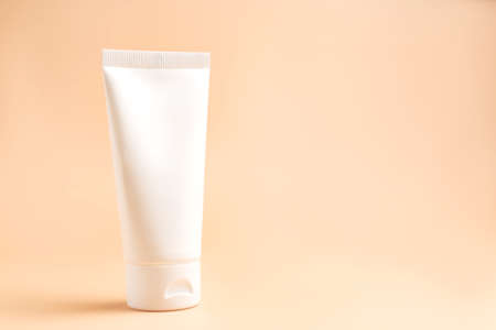 Cream tube on beige background. Cosmetic skincare product blank plastic package. White unbranded lotion, balm, hand cream, toothpaste mockup. Sunscreen cream bottle with copy spaceの写真素材