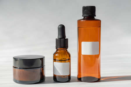 Cosmetic glass bottles with cream, toner and face mask on grey background with hard shadows. The concept of a beauty natural cosmetics.の写真素材