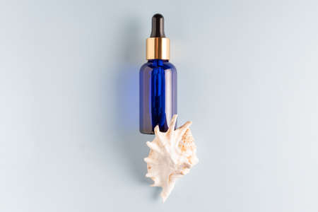 Serum bottle with pipette on blue background. Top view flat lay. Dermatology science cosmetic laboratory. Natural medicine cosmetic research, organic skin care products with sea minerals and collagen.の写真素材