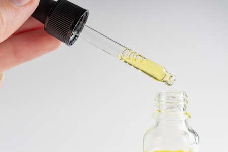 Woman hand holding serum glass bottle with pipette. Ascorbic Acid, Resveratrol, Caffeine Solution....