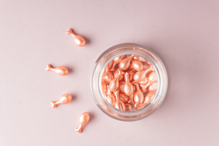 face care oil capsules on pink background. single use nourishing oil for dry and damaged skin. anti-aging cosmetics.の写真素材