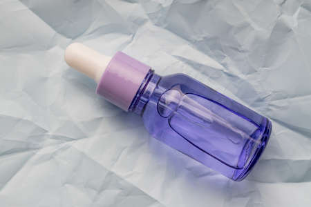 close up of face beauty oil or serum in transparent dropper bottle on blue background. Natural skin care cosmetics, unbranded packageの写真素材