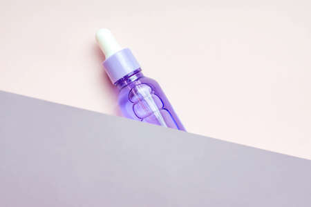 trendy shoot of skin care products. Face care serum in purple bottle on two colored background. unbranded packageの写真素材
