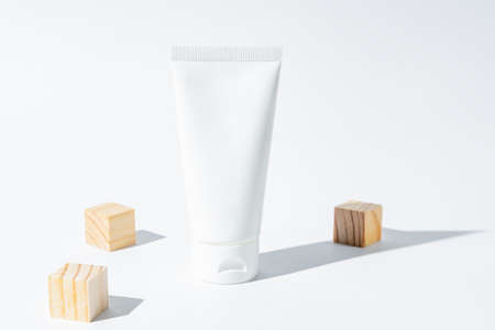 beauty spa medical cosmetic lotion cream in tube bottle packaging on white background with summer season sun light and scattered wooden cubes.の写真素材