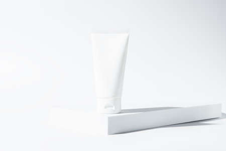 Creative and trendy product presentation with podium, sunlight and shadow. Beauty treatment skincare and cosmetic lotion cream mockup on white backgroundの写真素材