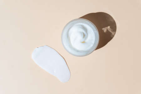 White cosmetic cream strokes on beige background. Skincare lotion face serum smear. beauty product...