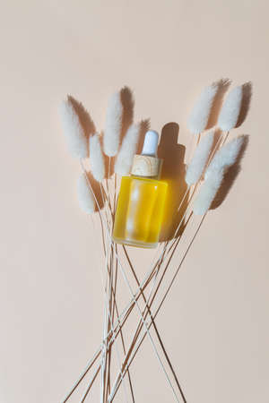 transparent frosted glass cosmetic bottle mock up and bouquet of dry Lagurus on beige background. top view. copyspace. Unbranded cosmetics for skincare.の写真素材