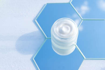 Moisturizer cream jar in frosted glass bottle on sky background. Close up of skin and body care beauty products texture.の写真素材