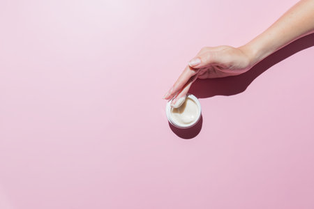 Woman hand with a cream on on a pink background. Groomed hands, natural short nails, m.ockup cosmeticsの素材 [FY310189020668]