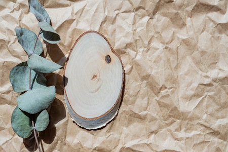 Empty round wooden podium for product presentation, eucalyptus branch on paper craft background. Background of natural materials for cosmetic advertising close-up, top view.の写真素材