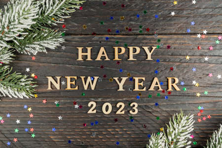 New Year's concept. Happy new year 2023 wooden text on a wooden background, fur-tree branch on the edge of the frame.の写真素材
