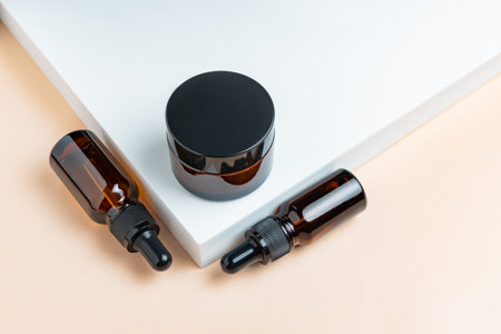 Natural skincare product in glass bottles with dropper. Serum for woman facial skin. Herbal mineral cosmetic on white podium. Dark glas package cosmetology with pipette. copyspace.の写真素材