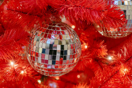 Silver disco ball on a red christmas tree. Festive new year backgroundの写真素材