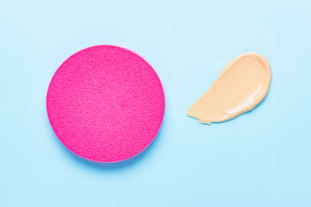 Makeup sponge for foundation cream, samples on blue color background. Skincare beauty blender. Flat lay swatches from tone cream and sponge, minimal aesthetic trendsの写真素材