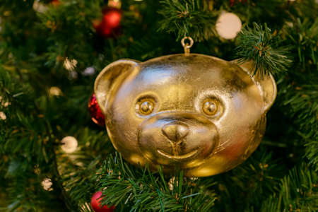 Christmas tree bauble in shape of golden teddy bear pn a fur tree. Festive greeting card for winter holidaysの写真素材