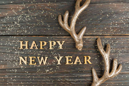Happy new year greeting card with wooden text and golden raindeer horns. Festive backgroundの写真素材
