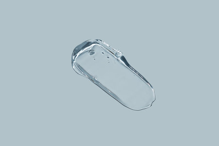Glycerin gel texture. Transparent serum stroke on blue background. Liquid gel moisturizer with...