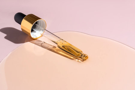 Yellow texture of a drop of whey or olive oil on a pink background. Transparent sample of cosmetic...
