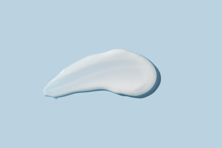 Cosmetic product smear white moisturizing lotion isolated on blue, squeezed out and smeared portion of skincare cream product testing.の写真素材