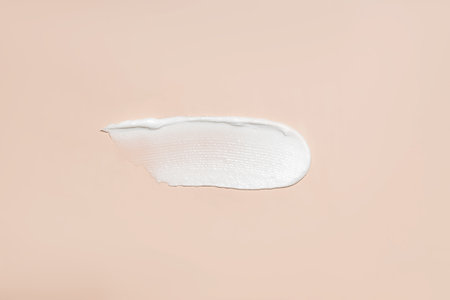 Cosmetic product smear white moisturizing lotion cream on beige, squeezed out and smeared portion of...