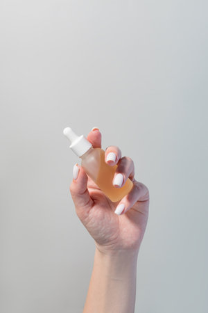 Woman hand holding serum glass bottle with pipette. Ascorbic Acid, Resveratrol, Caffeine Solution. Hydration of skin and eye contour. Skin care routine conceptの写真素材