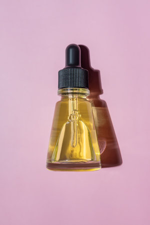 Anti aging serum in glass bottle with dropper on pink background. Facial liquid essential with collagen and peptides.の写真素材