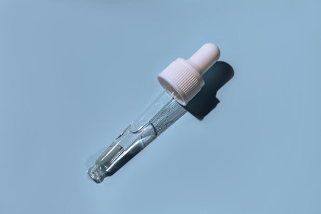 Dropper glass bottle branding mockup. cosmetic pipette. trendy blue background. Concept of organic and beauty cosmetics. Harsh sunshine. top viewの写真素材