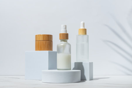 Trendy background with natural cosmetic skincare bottles. product presentation. Beauty and body care product concept. Beauty oil and face cream in white frosted glass bottles.の写真素材
