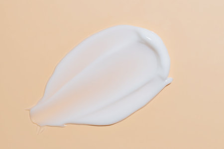 White cosmetic face cream or body lotion moisturizer strokes on pastel beige background. Hygiene, skincare product with creamy texture. Beauty face creme smear swatch on color background.の写真素材