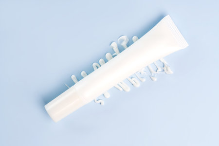 Cream tube on blue background. Cosmetic skincare product blank plastic package. White unbranded lotion, balm, hand cream, toothpaste mockup with cream smear texture. Sunscreen creamの写真素材