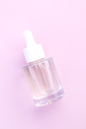 a modern glass dropper bottle on minimalist pink backdrop with space for text. Mockup for variety of products, from skincare serums to essential oilsの写真素材