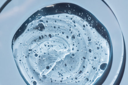Hyaluronic acid serum texture. Beauty skin care liquid gel on petri dish on blue background. Clear...