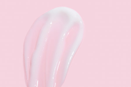 Smear of cosmetic cream or lotion on pink background. smear smudge stroke on color background. Creamy beauty product closeupの写真素材