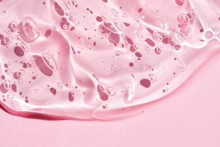 Gel serum texture background. pink skin care liquid swirl. Clear cosmetic cream with bubbles closeup on pinkの写真素材