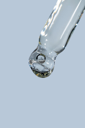 cosmetic dropper with bubbles close-up isolated on blue background