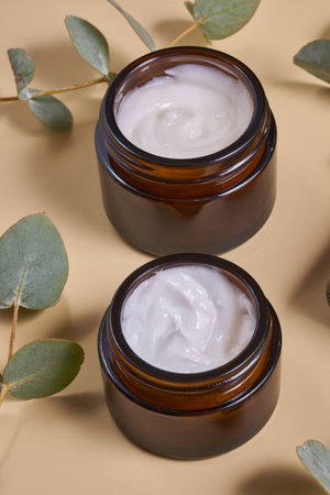 Set of moisturizer cream jar in amber glass bottles and dry eucalyptus on beige background. Set for skin and body care beauty productsの写真素材