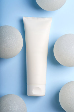 Creative new year and Christmas presentation of cosmetics packaging. White Plastic unbranded cream tube with white baubles on blue background. Trendy mockup for you brandの写真素材