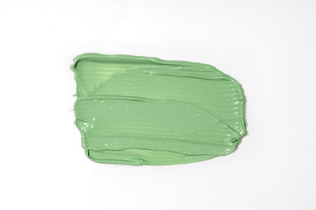 Green mud mask swatch on white background. Close up of cosmetic product smear, concealer, kaolin or...