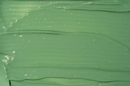 Green cosmetic clay facial mask, cream, body scrub texture close up, top view. Abstract background with brush strokes.の写真素材