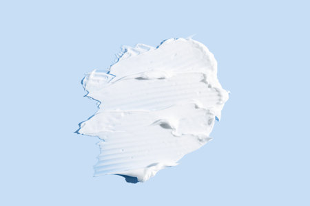 Cosmetic product smear white moisturizing lotion isolated on blue, squeezed out and smeared portion of skincare cream product testing.の写真素材