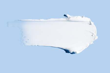 Face cream stroke isolated on blue background. White exfoliation cream smear smudge sample. face or body skincare product swatch. showcase of the productの写真素材