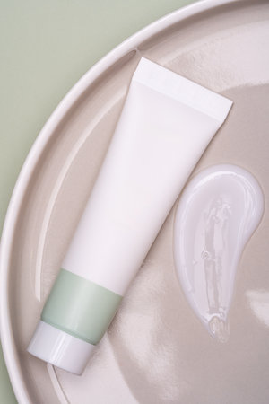 Squeeze plastic cream tube and cream stroke on ceramic plate. Unbranded package for face cream or mask. Skin care beauty treatment presentation. Mockupの写真素材