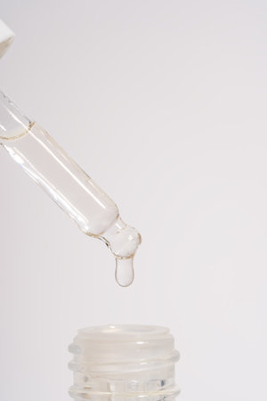 Close-up of a cosmetic bottle with a pipette showing the texture of the serum. Glass dropper with...