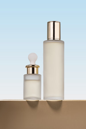 two cosmetic product mockups on golden podium. Background for presentation of cosmetic. Hero view. Face serum dropper bottle and tonerの写真素材