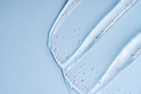 Close-up shot of blue liquid cosmetic gel or serum makeup swatches with a glossy, shiny texture on a...