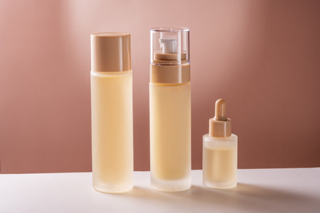 Set of beauty products in glass matte bottles on white table on brown background. Skin care set for daily routine. Mockup for designers. Unbranded packageの写真素材