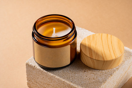 Mock-up of aroma soy candle in amber glass jar on natural stone pedestal. Scented cozy atmosphere for relax and spa on brown background, mockupの写真素材