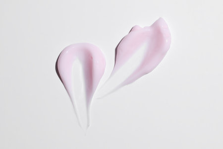 Texture of pink cream on white background. Smear of moisturizer close up. Lotion swatch. Beauty skin care product smear smudge. SPF sunscreen cream sample on whiteの写真素材