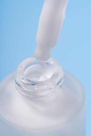frosted cosmetic bottle with pipette on blue background, product packaging, anti aging serum with peptides, cosmetics mockup, spa conceptの写真素材